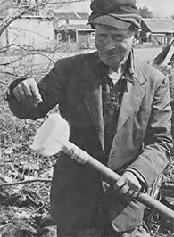 The author displays a gardening implement of his own invention: a plastic jug head attached to a plastic pipe. It's not for soil building but seed planting—stick the end of the pipe in the ground, put your seeds in the jug, and funnel them down.